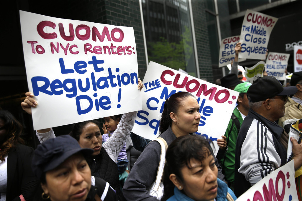 FILE--In this May 6, 2015 file photo, protesters hold signs during a demonstration in front of New York Gov. Andrew Cuomo's offices in New York. Albanys latest corruption cases focus on New York City real estate interests seeking tax breaks from politicians, in particular an exemption worth about $1 billion a year that legislators and the governor must now decide whether to extend. (AP Photo/Seth Wenig, File)